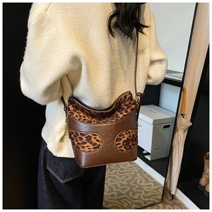 Detail view of retro leopard print bucket bag styled with a white sweater and jeans