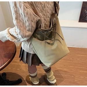Sac cabas en daim vert olive avec anse en cuir marron et nœud porté par un mannequin