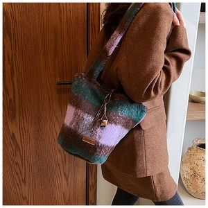 Detail view of multicolored plush bucket bag with leather tag worn by a model