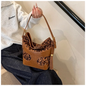 Close-up of brown leather hobo bag with leopard print patches and tassel detail