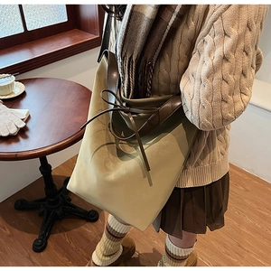 Détail du cordon à nœud papillon et texture de cuir givré sur le sac seau kaki