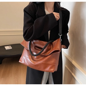 Detail of vintage brown PU tote bag with unique black twisted rope handle and wide strap