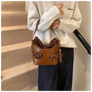 Detail of a brown bucket bag with leopard print texture and decorative leather fringe