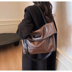 Detail of brown soft PU leather handbag with circular handle and wide nylon strap