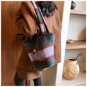 Close-up of the plush striped tote bag featuring a purple and green texture and leather logo