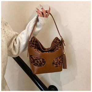 Detail view of brown PU leather and leopard print fabric handbag with tassel decoration