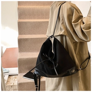 Detail view of black PU suede tote bag with drawstring bow on khaki trench coat