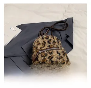 Détail d'un mini sac à dos en peluche léopard avec bordures en cuir sur une veste de costume