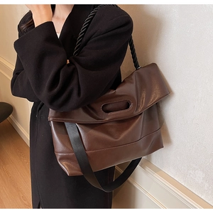 Detail view of large brown leather tote bag with woven rope strap and canvas strap