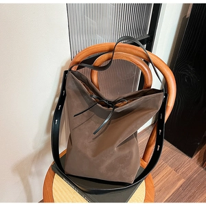 Grand sac cabas en daim marron foncé avec bandoulière en cuir sur une chaise