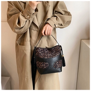 Detail of leopard print bucket bag with black tassels and gold bead on trench coat