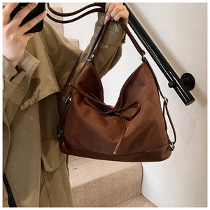 Detail of a large brown matte PU leather tote bag with a decorative drawstring bow