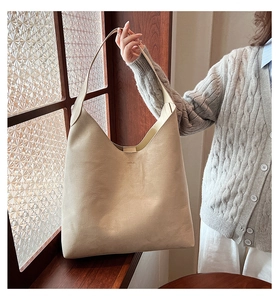Close-up of minimalist beige PU leather tote bag showing soft texture and wide shoulder strap