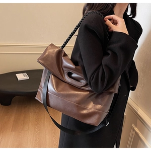 Detail of dark brown faux leather tote bag showing crossbody strap and flap closure
