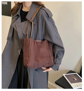 Détail du grand sac cabas marron en daim synthétique porté avec un manteau en laine gris