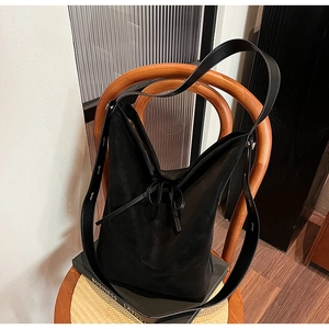 Grand sac fourre-tout en daim noir avec nœud en cuir sur une chaise en bois vintage