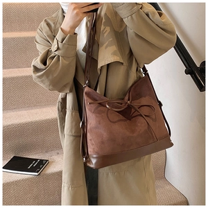 Detail view of brown frosted suede tote bag with leather piping and bow tie detail