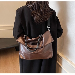 Detail of dark brown faux leather tote with thick woven handles and detachable strap