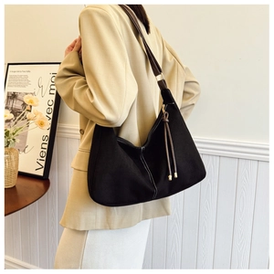 Detail view of large black tote bag with white stitching and leather strap on model