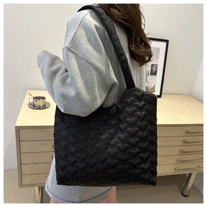 Detailansicht der schwarzen Stepptasche mit Herzmuster und breitem Schultergurt aus Nylon