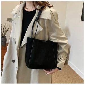 Sac fourre-tout noir minimaliste mat porté avec un trench beige pour un style urbain chic