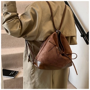 Detail of a brown frosted PU leather bucket bag with drawstring closure and slim shoulder straps