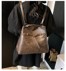 Detail of vintage dark brown faux leather backpack with metallic buckle and fine stitching