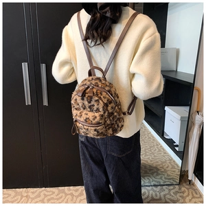Détail d'un sac à dos en peluche à motif léopard avec des bretelles en cuir marron