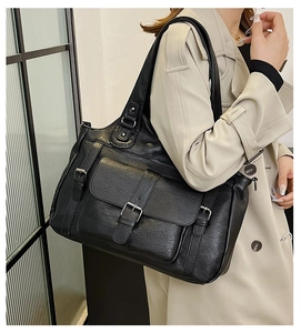 Detail shot of black tote bag featuring premium leather texture and front buckle pocket design