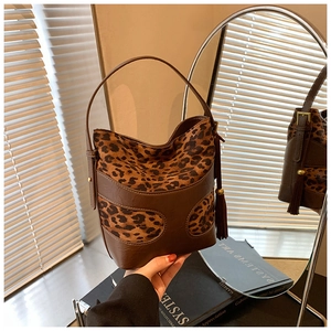 Retro leopard print bucket bag with brown leather trim and tassel on mirror surface