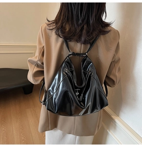 Gros plan du sac à dos en cuir noir brillant avec forme géométrique et fermoir en métal argenté