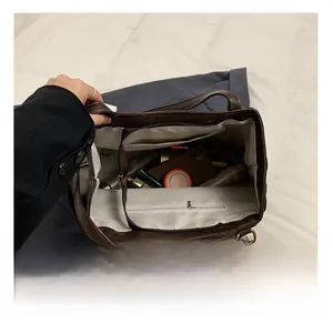 Detail view of the large capacity interior with zip pocket in dark brown leather tote bag