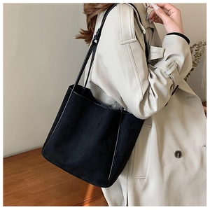 Gros plan détaillé sur la texture en daim noir et les fines lanières du sac cabas pour femme