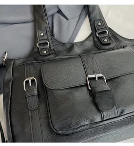 Close-up of black PU leather tote bag featuring litchi texture and silver metal buckle details