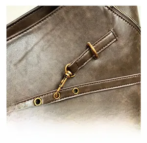 Close-up of vintage oil wax leather texture and premium brass hardware on the tote bag