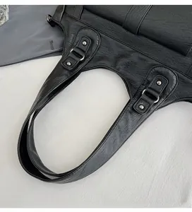 Close-up of black textured leather tote bag with metal rivet handle reinforcements