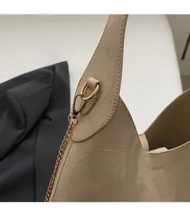 Detail of khaki suede shoulder bag with gold chain strap and embossed VEILA brand logo