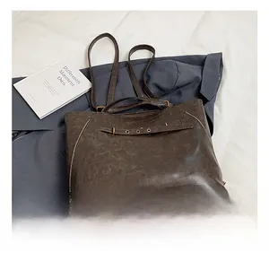 Detail of dark brown wax leather tote with vintage texture and functional zippers