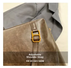 Detail of adjustable metal buckle strap and side zipper on brown oil wax leather tote bag