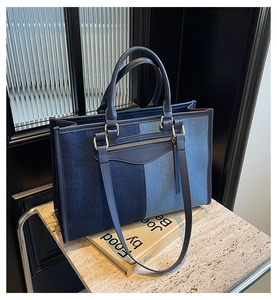 Detail of color-block tote bag featuring navy blue panels and golden metal zipper accents