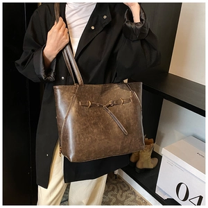 Detail view of brown wax leather tote bag with golden metal lock and textured finish