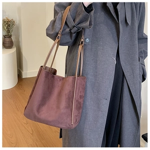 Détail du cabas en daim marron foncé avec bandoulière réglable dans un décor minimaliste