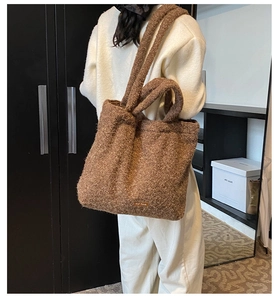 Brown fuzzy teddy tote bag shown on shoulder featuring soft fleece texture and leather logo