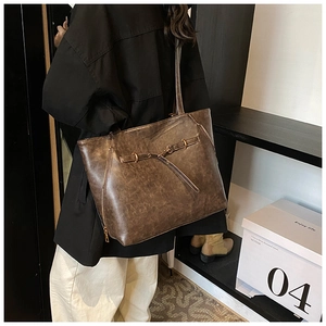 Close-up of brown vintage waxed leather tote bag showing side zipper and strap detail