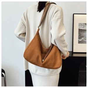 Model wearing a caramel hobo shoulder bag with leather straps in an indoor setting