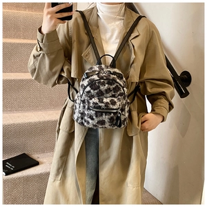 Gros plan d'un mini sac à dos en peluche léopard porté par un mannequin en manteau