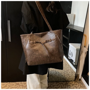 Close-up of deep brown oiled leather tote with vintage strap buckles and brass hardware