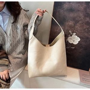 Detail of a large beige soft PU leather hobo bag worn over the shoulder in an artistic setting