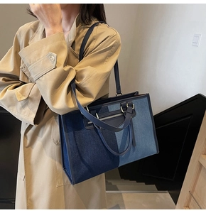 Detail of color-block denim tote bag shown with model in a stylish trench coat