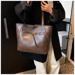 Detail of vintage oil wax leather tote bag showing textured finish and buckle strap